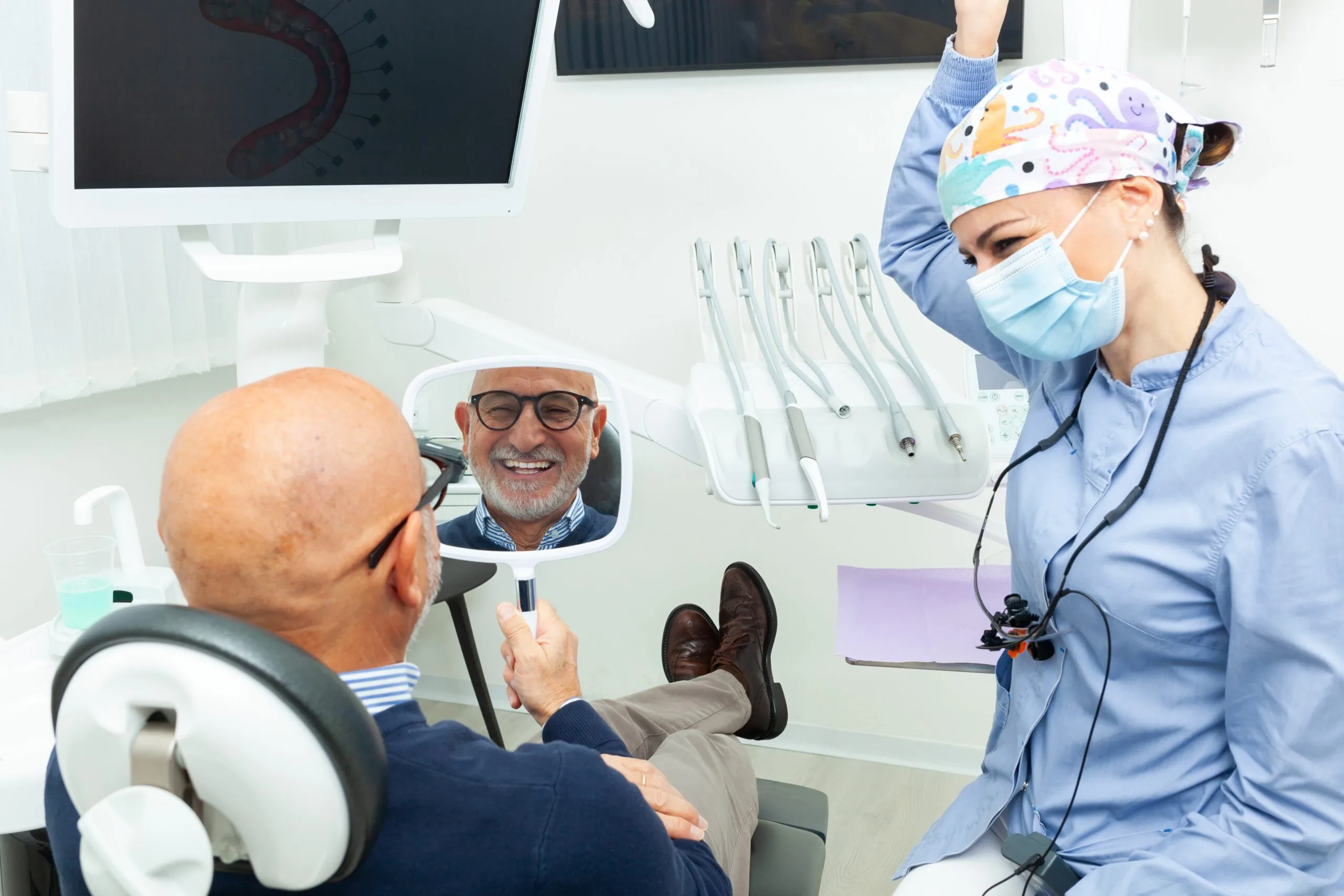 Happy senior man looking at his new smile in the mirror after a successful dental implant surgery