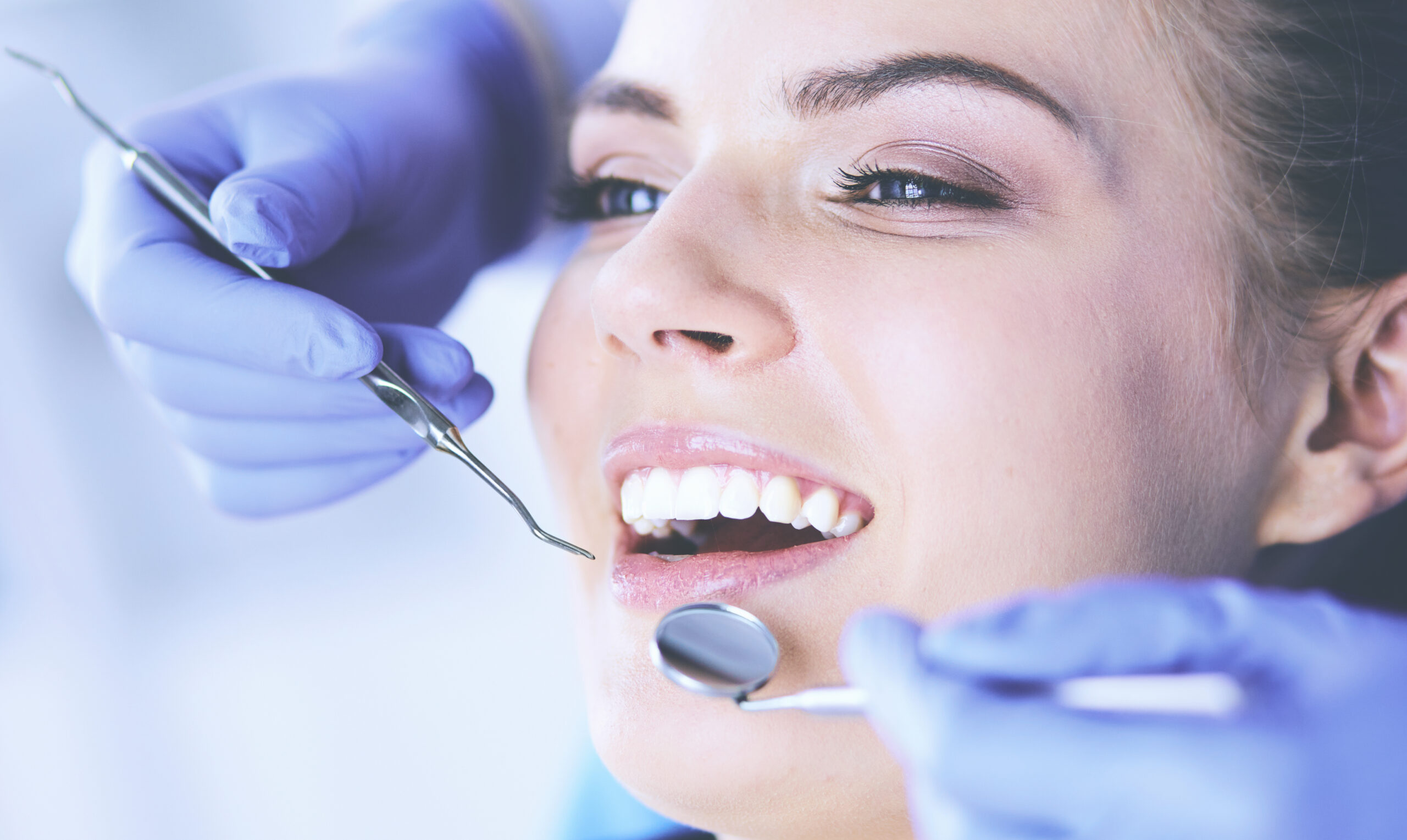 Young Female patient with open mouth examining dental inspection at dentist office