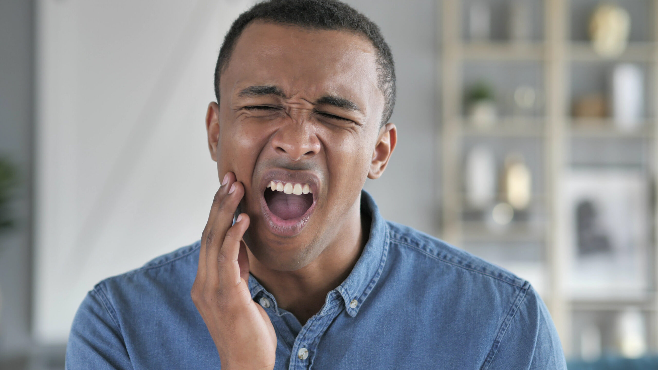 young man holding his jaw in pain, bruxism signs