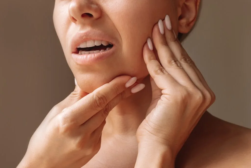 woman holding her jaw from impacted wisdom teeth pain before wisdom teeth removal in Hilliard, OH