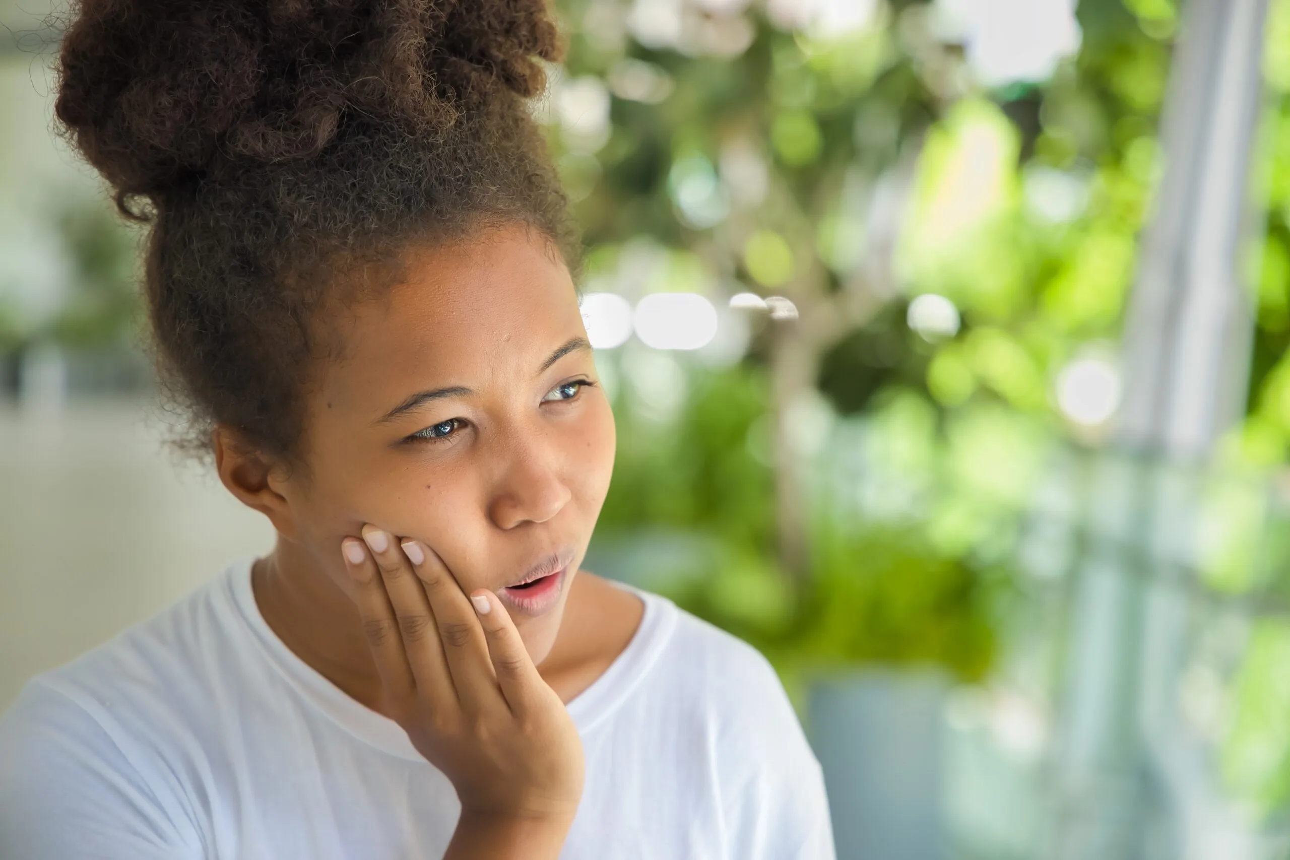 young woman holding her jaw in wisdom tooth pain