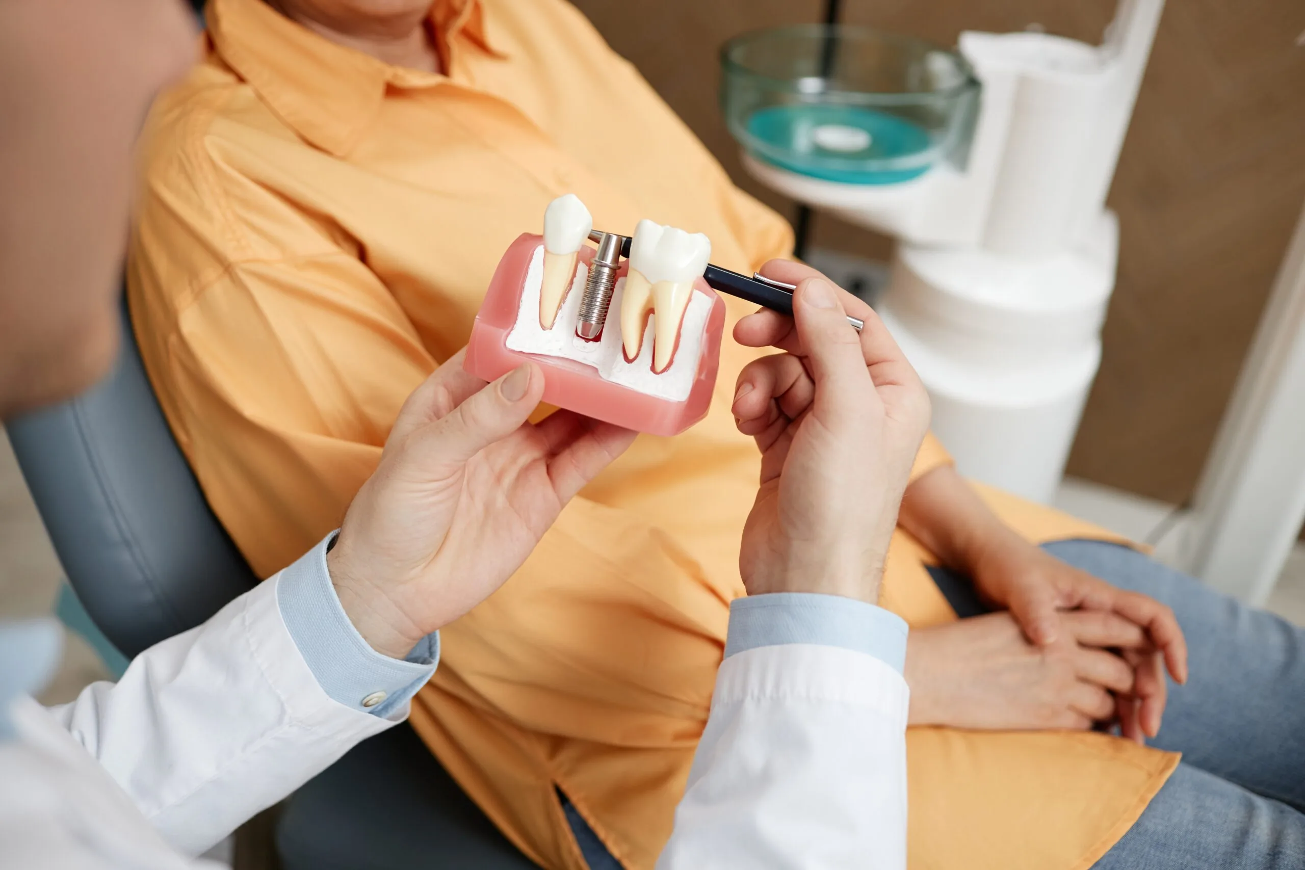 closeup of a dental professional showing a patient an implant model